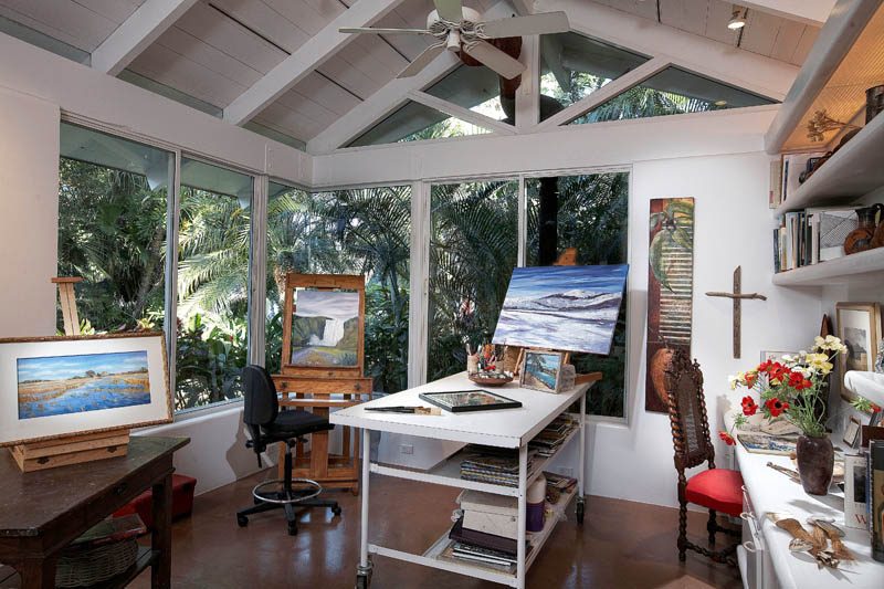 The interior of a backyard art studio with vaulted ceilings and full-height windows